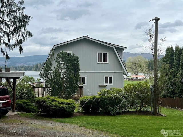 view of property exterior featuring a lawn and a deck with mountain view