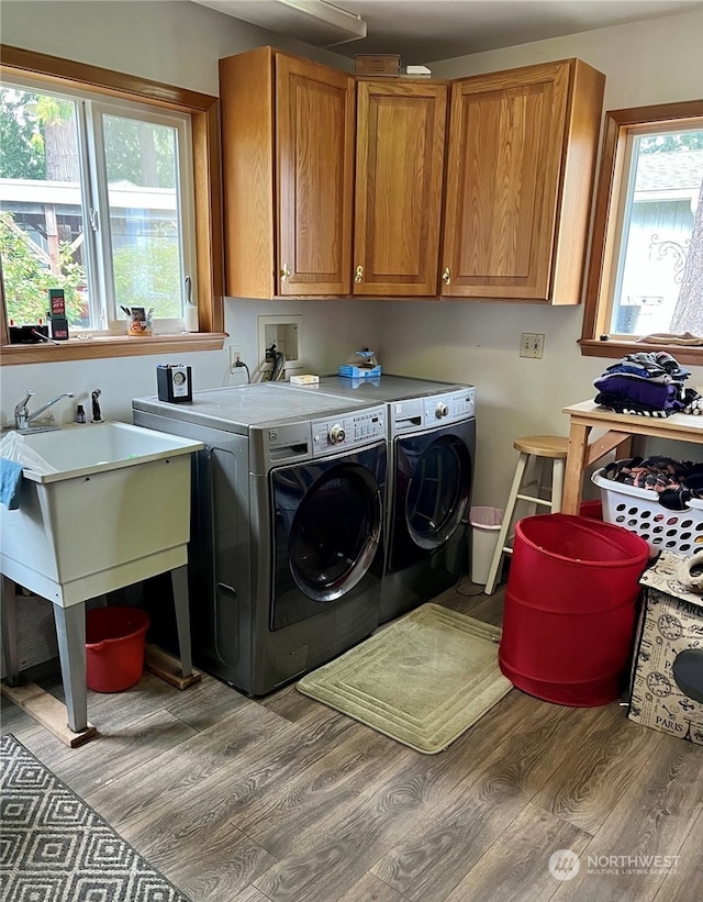 laundry room with light wood-type flooring, washing machine and clothes dryer, and cabinets