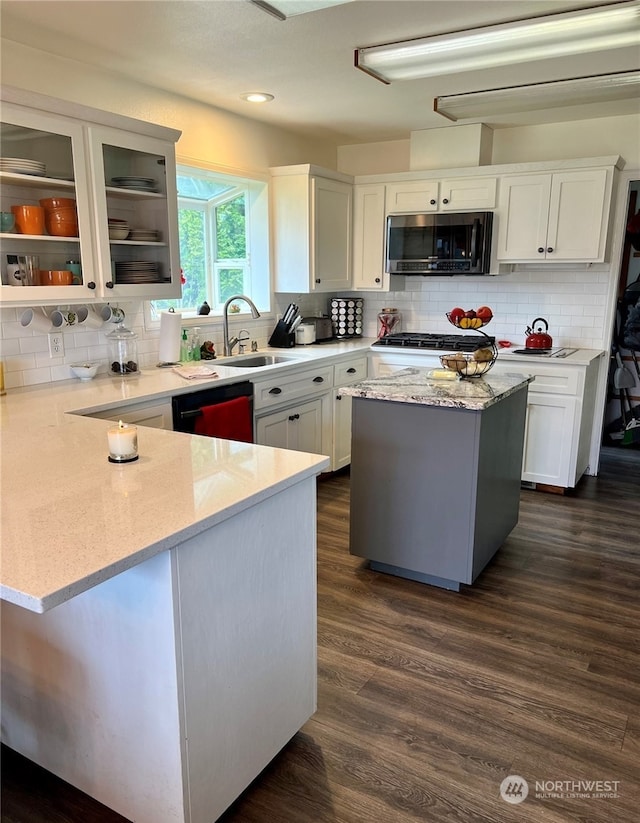 kitchen with light stone counters, sink, white cabinets, and dishwasher