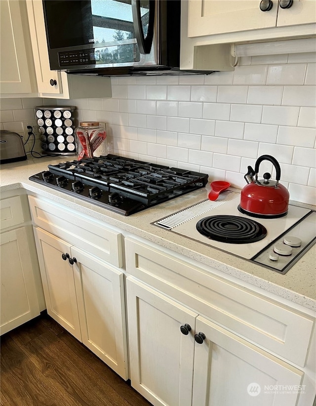 kitchen featuring tasteful backsplash, white electric stovetop, dark hardwood / wood-style flooring, and black gas stovetop