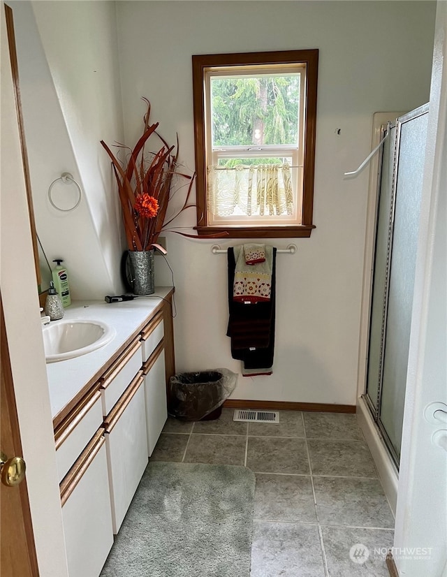 bathroom featuring tile patterned flooring, a shower with shower door, and vanity