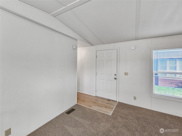 carpeted empty room featuring lofted ceiling