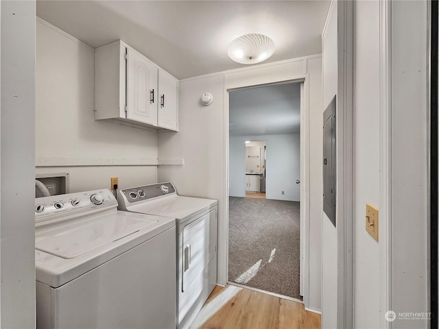 clothes washing area featuring cabinets, light hardwood / wood-style flooring, and washing machine and clothes dryer