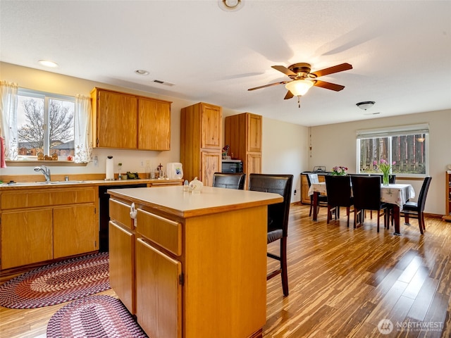 kitchen featuring a center island, light countertops, visible vents, light wood-style floors, and a sink