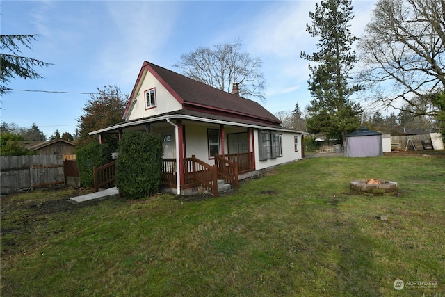 view of home's exterior with a storage shed, a yard, covered porch, and an outdoor fire pit