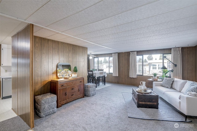 living room with ceiling fan, light colored carpet, and wooden walls