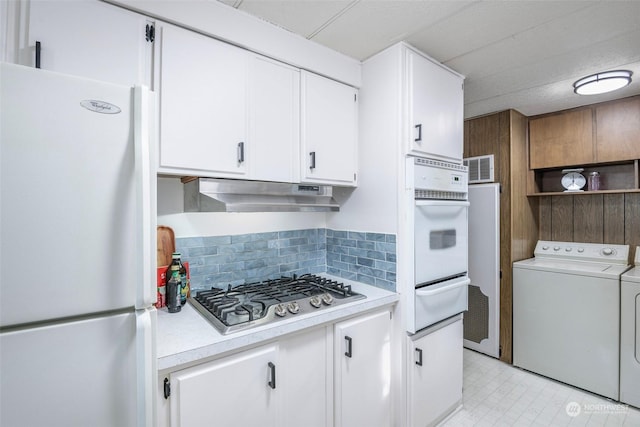 kitchen with white appliances, white cabinetry, washing machine and dryer, and backsplash