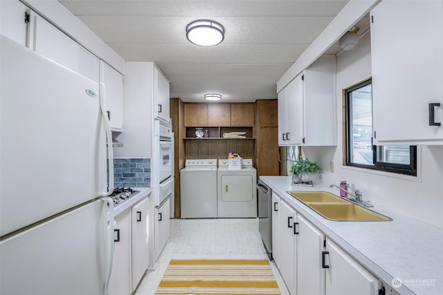 kitchen with white cabinets, stainless steel appliances, washer and clothes dryer, and sink