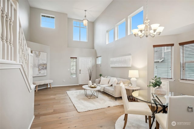 living room featuring a high ceiling, light wood-type flooring, and an inviting chandelier