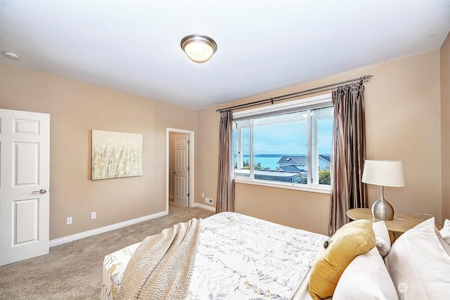 bedroom featuring light colored carpet and a water view