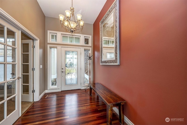 foyer entrance with dark wood-type flooring, a wealth of natural light, and a chandelier