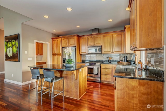 kitchen with a center island, dark wood-type flooring, dark stone counters, sink, and stainless steel appliances