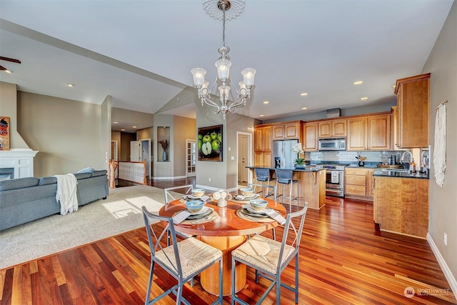 dining area featuring a chandelier, vaulted ceiling, light hardwood / wood-style flooring, and sink