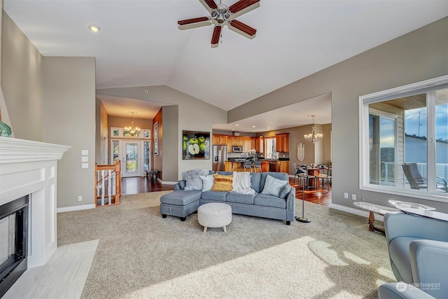 living room featuring ceiling fan with notable chandelier, a healthy amount of sunlight, light colored carpet, and lofted ceiling