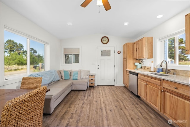 kitchen with hardwood / wood-style floors, dishwasher, sink, vaulted ceiling, and light stone countertops