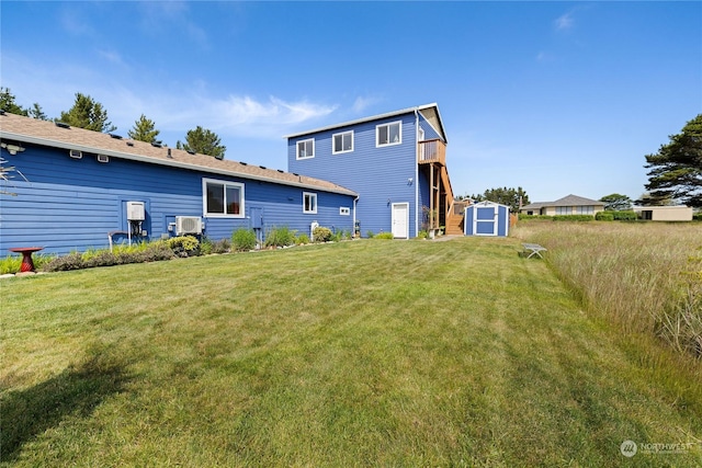 back of property with a lawn, an AC wall unit, and a storage shed