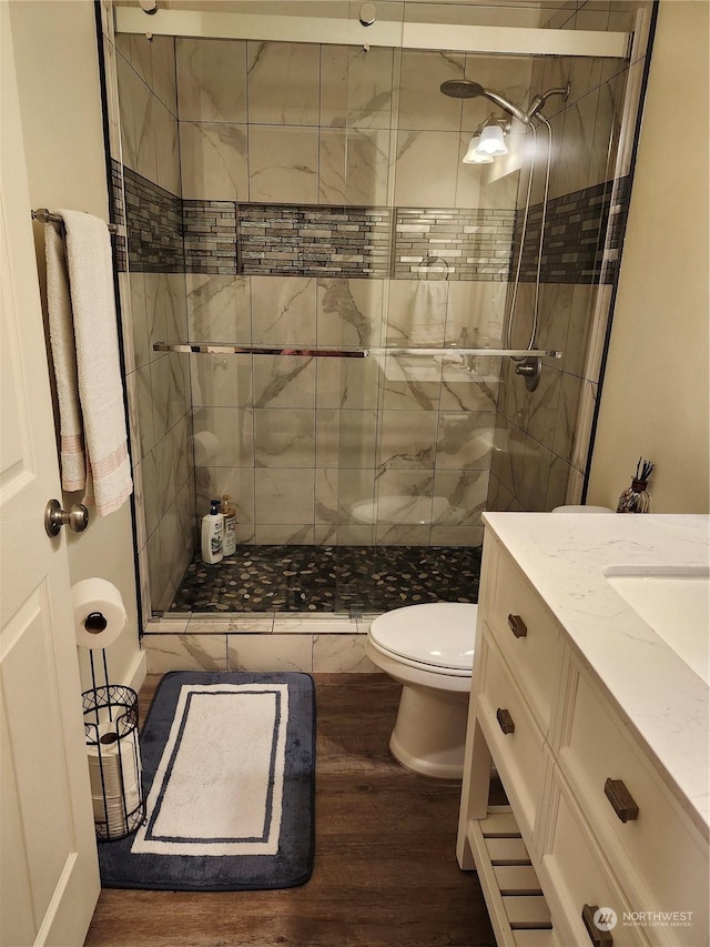 bathroom featuring walk in shower, vanity, wood-type flooring, and toilet