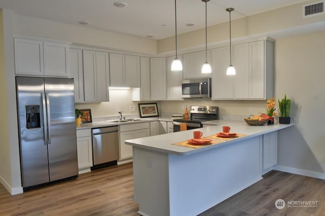 kitchen featuring sink, white cabinetry, kitchen peninsula, and appliances with stainless steel finishes