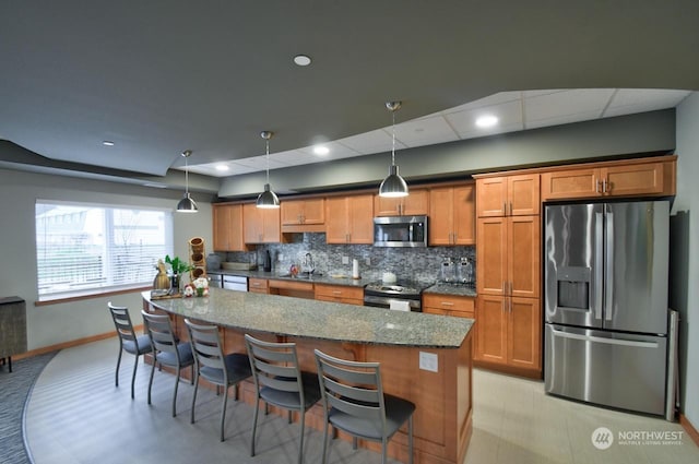 kitchen with stainless steel appliances, hanging light fixtures, and a kitchen bar