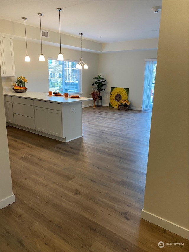 kitchen with dark wood-type flooring, white cabinetry, and pendant lighting