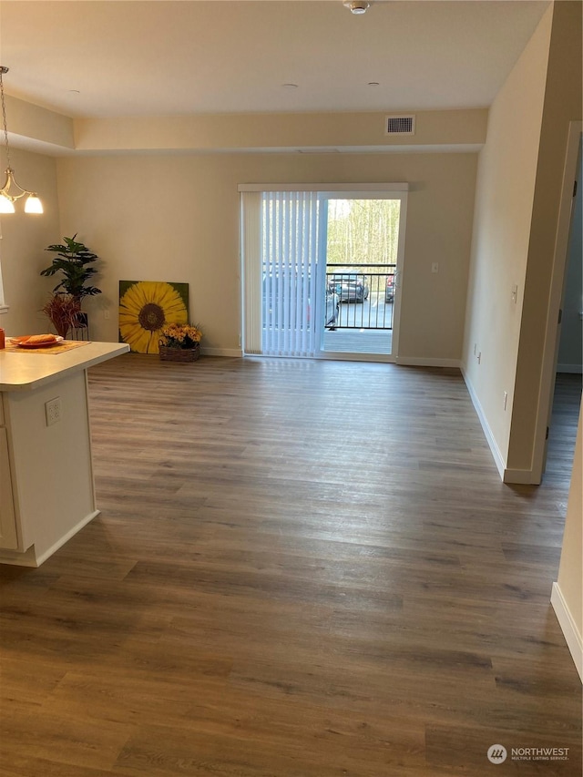 unfurnished room featuring an inviting chandelier and dark hardwood / wood-style flooring