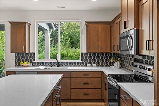 kitchen featuring decorative backsplash, sink, light stone countertops, and appliances with stainless steel finishes