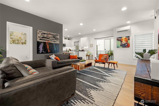 living room with a wall mounted air conditioner and light hardwood / wood-style flooring