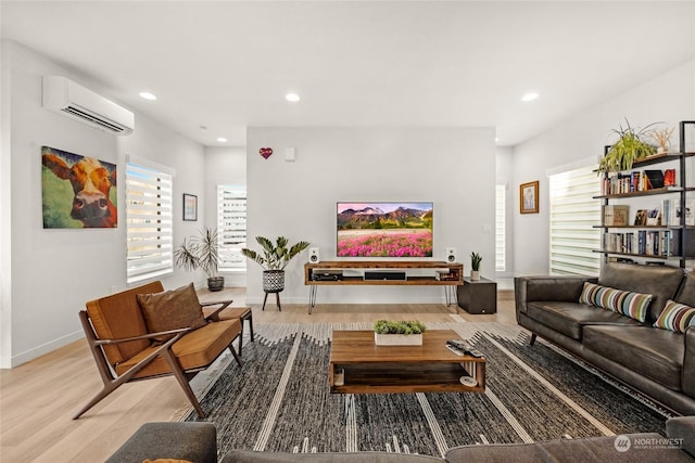 living room featuring light hardwood / wood-style flooring, a wall mounted AC, and a healthy amount of sunlight