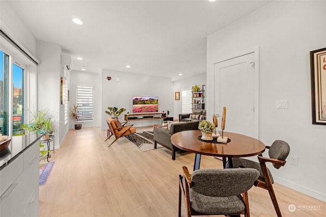 dining room featuring a wall unit AC and light hardwood / wood-style flooring