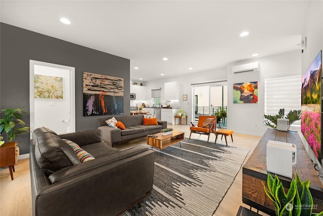 living room with a wall mounted air conditioner and light hardwood / wood-style flooring