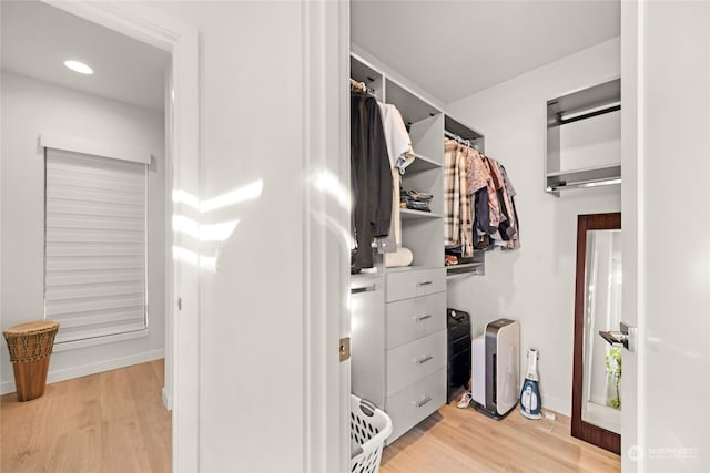 walk in closet with light hardwood / wood-style flooring