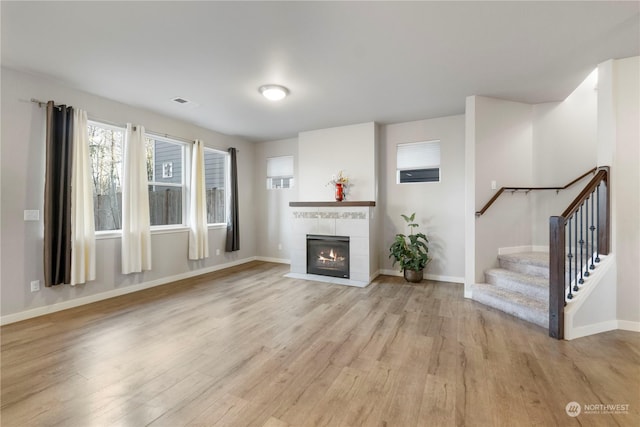 unfurnished living room with a tiled fireplace and light hardwood / wood-style flooring