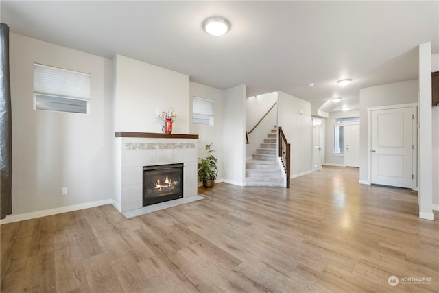 unfurnished living room featuring a tiled fireplace and light wood-type flooring