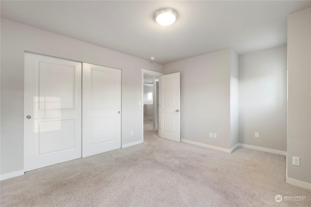 unfurnished bedroom with light colored carpet and a closet