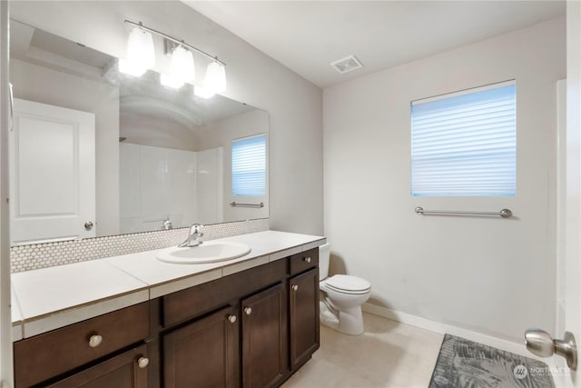 bathroom with vanity, decorative backsplash, and toilet