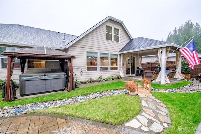 rear view of house with a gazebo, a patio, a hot tub, and a yard