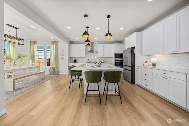 kitchen featuring light hardwood / wood-style floors, white cabinetry, and wall chimney range hood