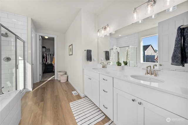 bathroom with hardwood / wood-style floors, vanity, and an enclosed shower