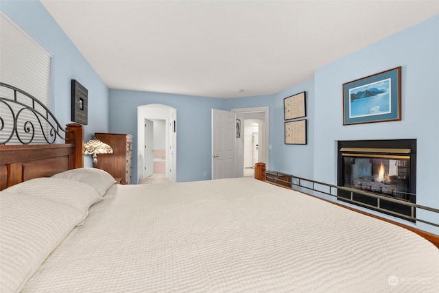 bedroom with a multi sided fireplace and ensuite bathroom