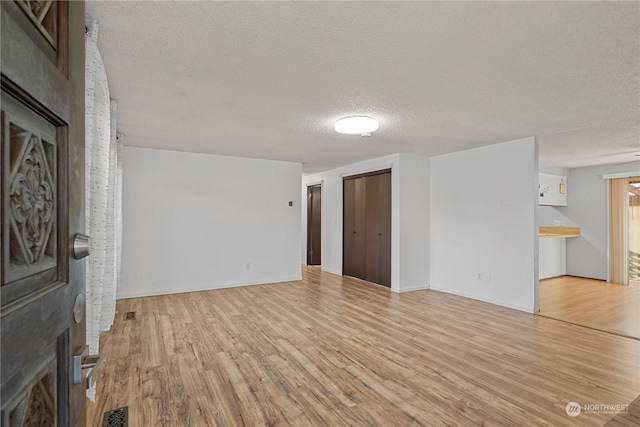 unfurnished room with a fireplace, light hardwood / wood-style flooring, and a textured ceiling