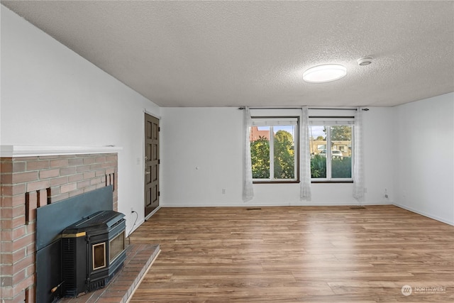 unfurnished living room with a wood stove, hardwood / wood-style floors, and a textured ceiling