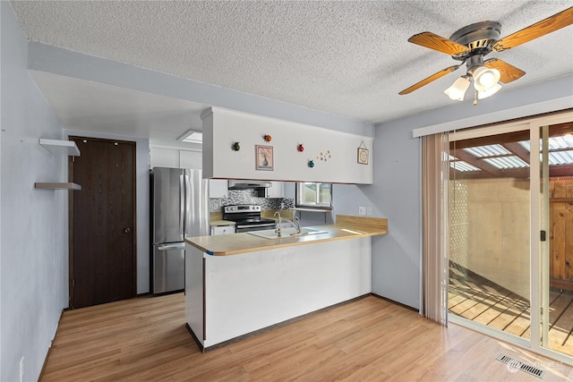 kitchen featuring light hardwood / wood-style floors, white cabinetry, kitchen peninsula, and appliances with stainless steel finishes