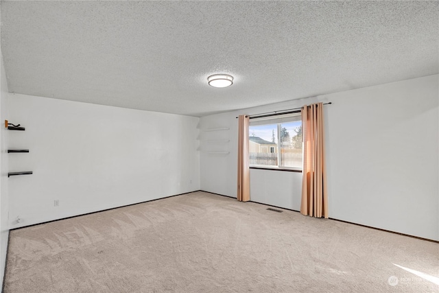 spare room with a textured ceiling and light carpet