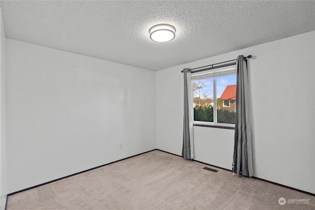 carpeted empty room with a textured ceiling