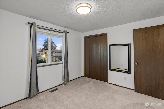 unfurnished bedroom featuring a closet, light colored carpet, and a textured ceiling