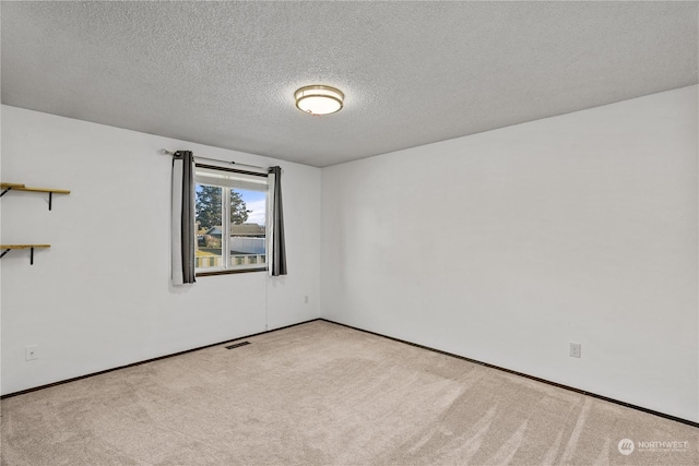 carpeted empty room featuring a textured ceiling