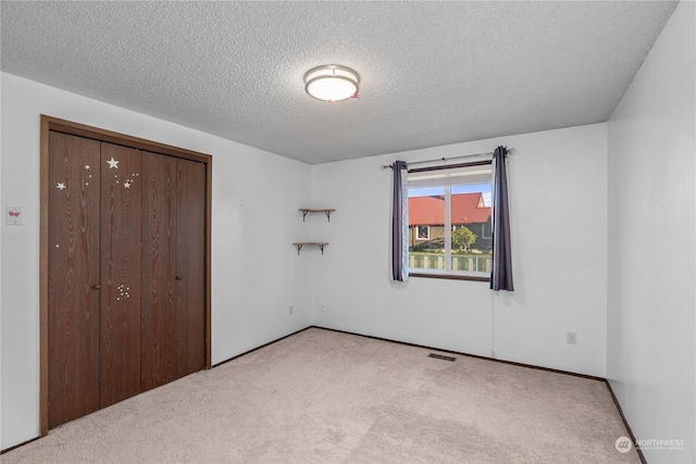 unfurnished bedroom with light carpet, a closet, and a textured ceiling