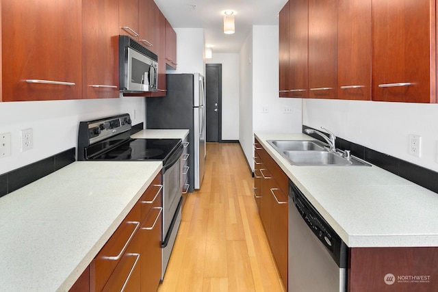 kitchen with sink, stainless steel appliances, and light hardwood / wood-style floors