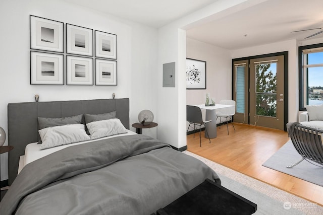 bedroom featuring electric panel, access to outside, and light hardwood / wood-style flooring