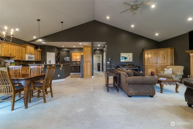 carpeted living room with sink, high vaulted ceiling, and ceiling fan with notable chandelier